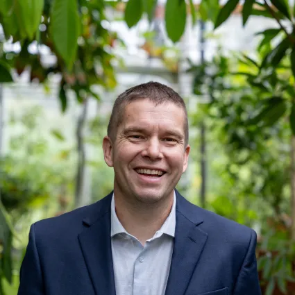 Man with light brown hair in blue blazer and light blue button down shirt.