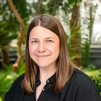 Woman with medium brown hair wearing a button down collared black shirt.