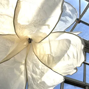 Close up of paper covered flower sculpture against blue sky.