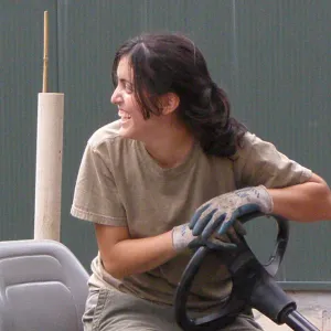 Student with brown hair in pony tail and tan clothes driving a work buggy.