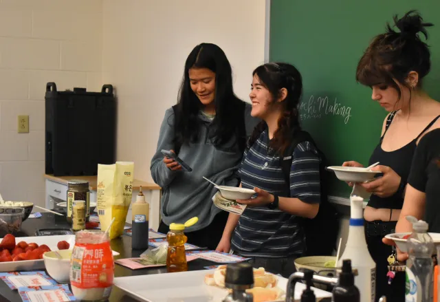 Student with black hair smiling with a bowl of mochi in hand.