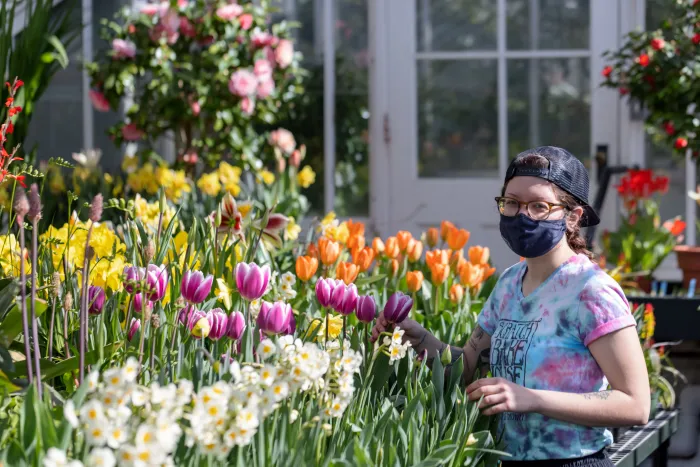 A student in a mask near a display of flowers