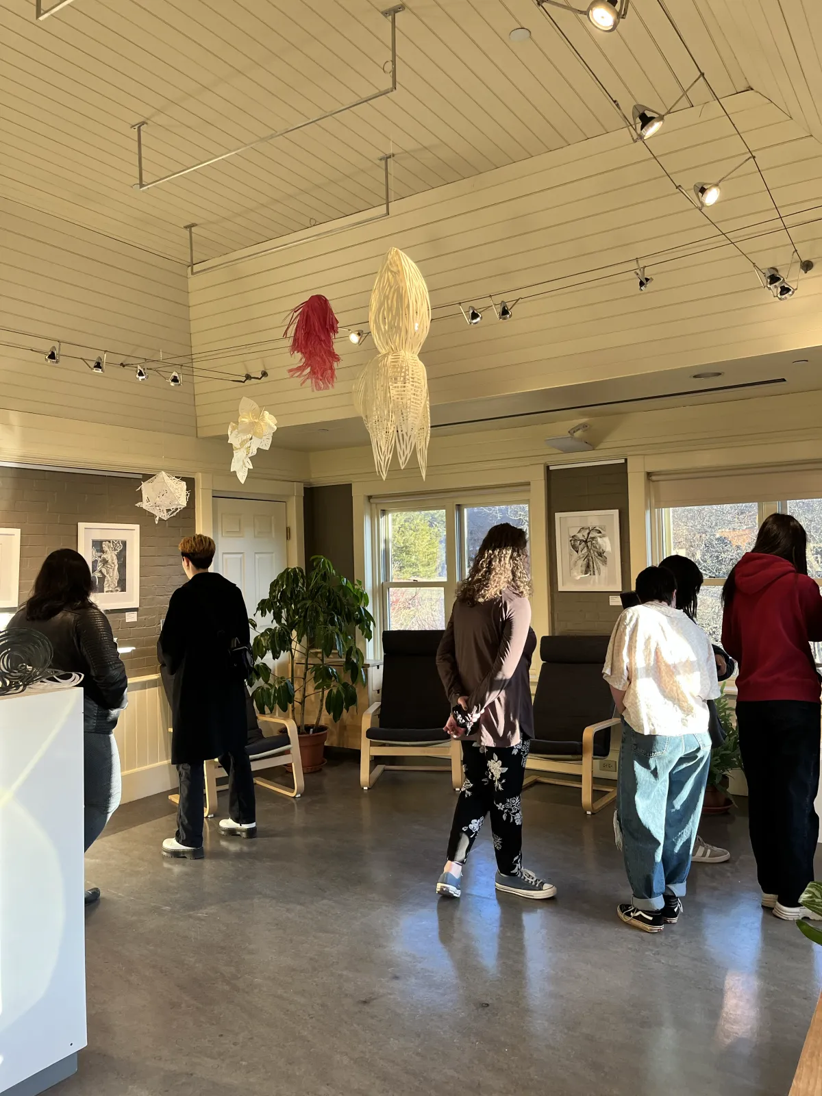 People in a gallery space with grey walls.