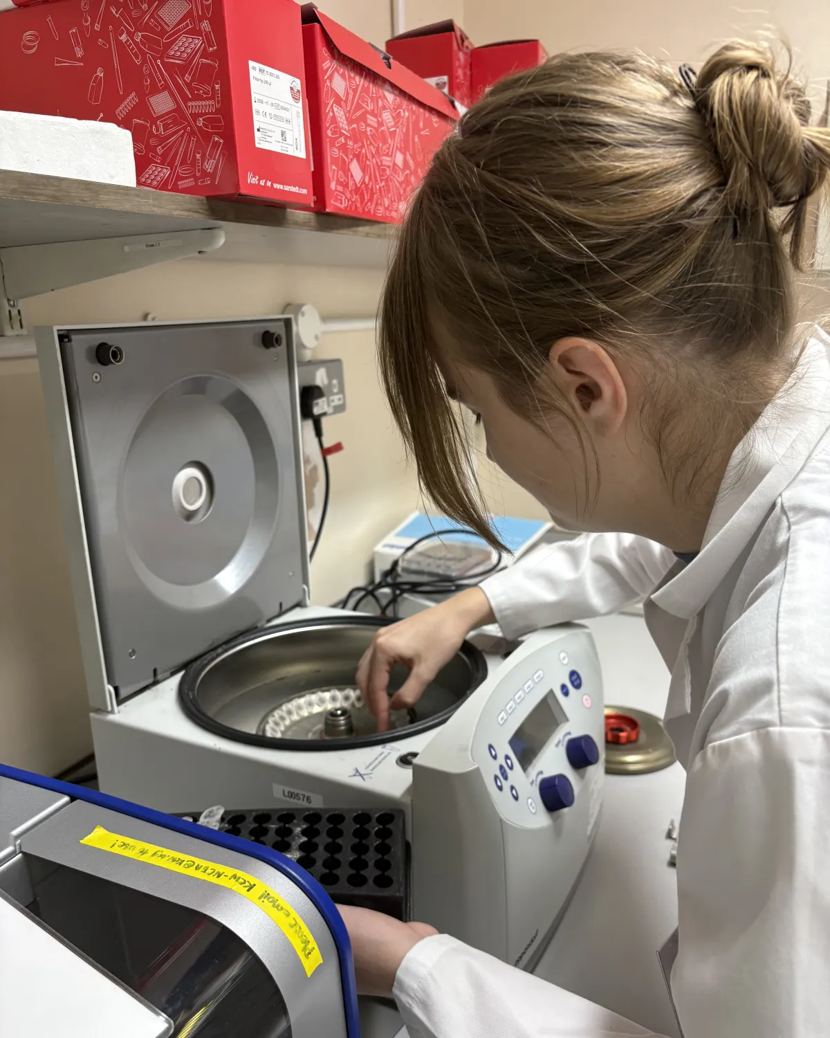 Woman with hair in bun and white coat working in lab.