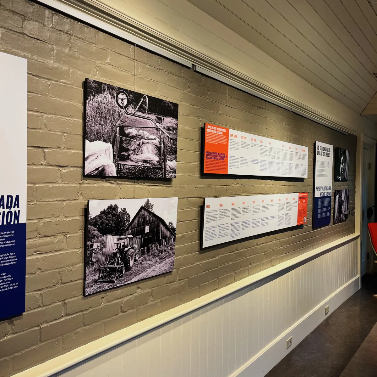 Grey ehibit space brick wall with black and white photos hanging and text panels.