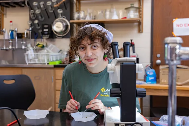 College student with purple bandana at a microscope. 