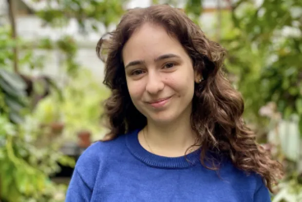 Girl with long brown curly hair and blue sweater.